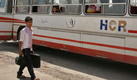 A boy with suitcase boarding a bus to leave the UNHCR voluntary repatriation centre in Dogharoun.