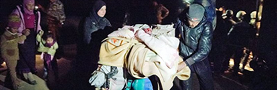 A man uses a stroller to carry his posessions across the Syrian border at night