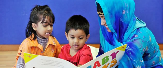 Woman reading a picture book with 2 young children